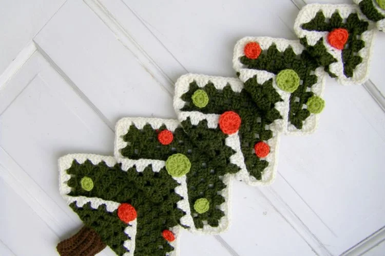 A crocheted christmas tree hanging on a door.