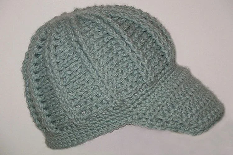 A blue knitted hat on top of a white surface.