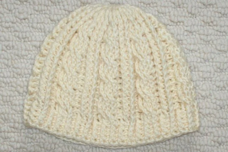 A white knitted beanie on a white blanket.