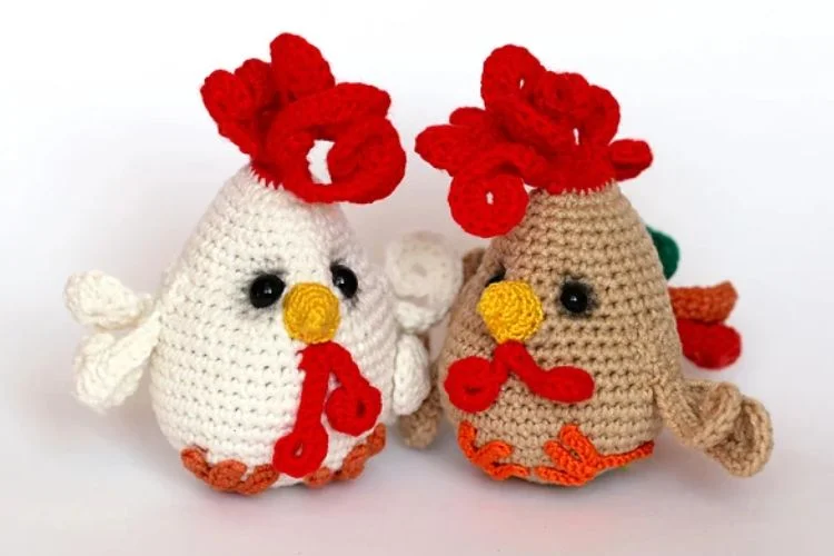 Two crocheted chickens sitting next to each other.