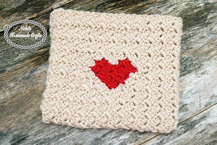 A crocheted ipad cover with a red heart on it.