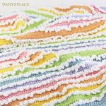 a rainbow crochet baby blanket with ruffled details