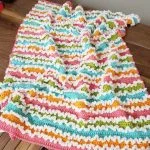 a crochet rainbow blanket with ruffles