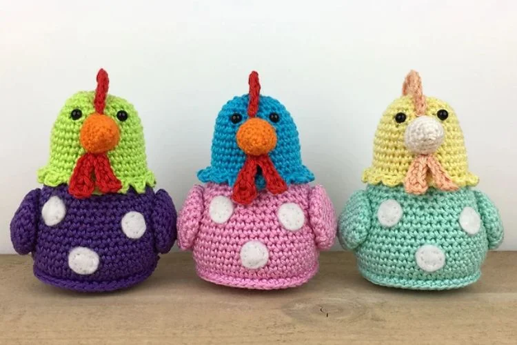 Three crocheted chickens in different colors.