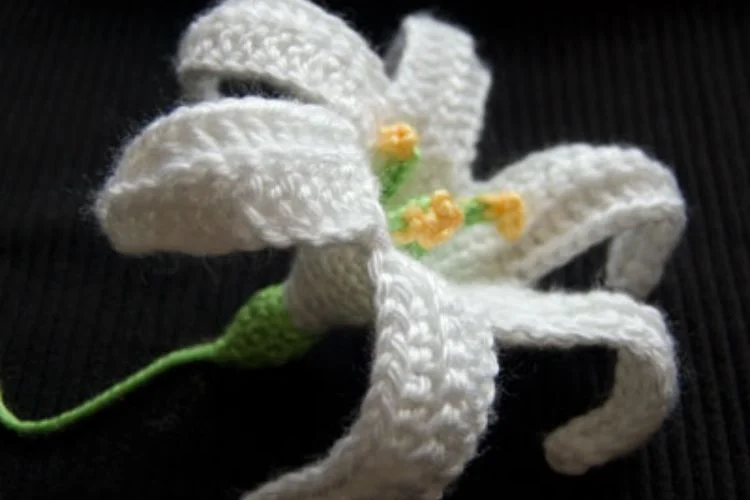 A white crocheted lily on a black background.