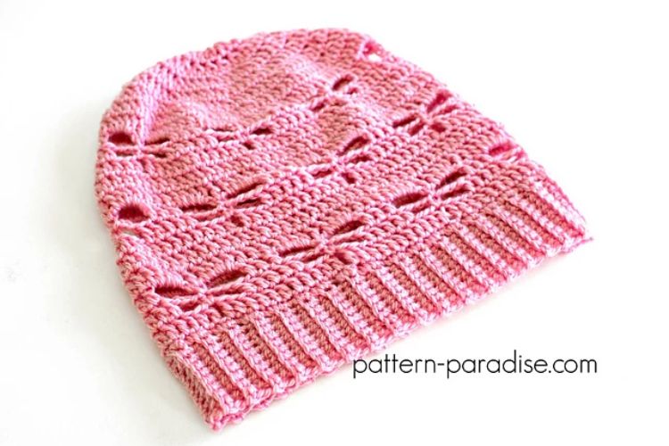 A pink crocheted beanie on a white surface.