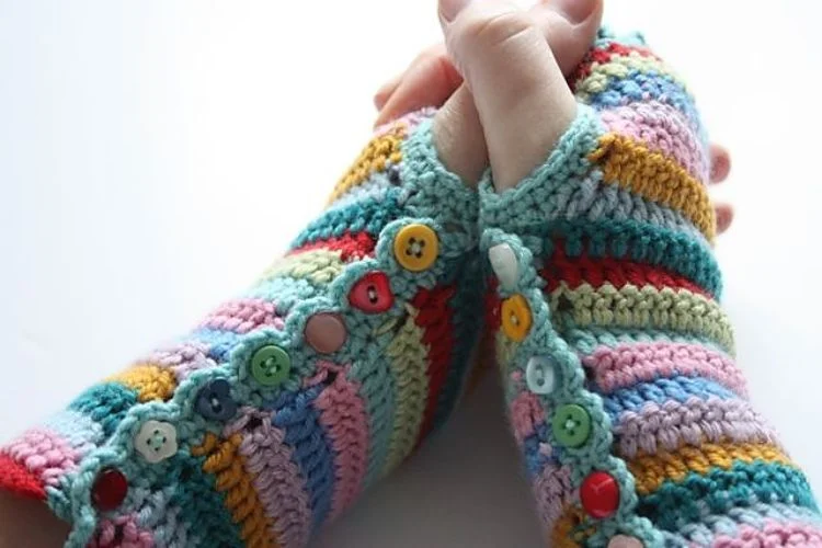 A pair of stripy crocheted fingerless mitts with buttons.