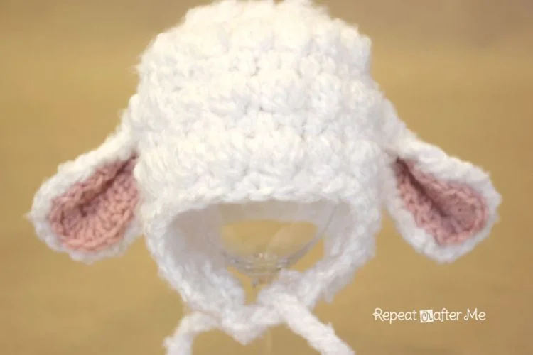 A white crocheted lamb hat with pink ears.