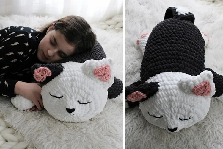 A girl is sleeping on a crocheted cat stuffed animal.