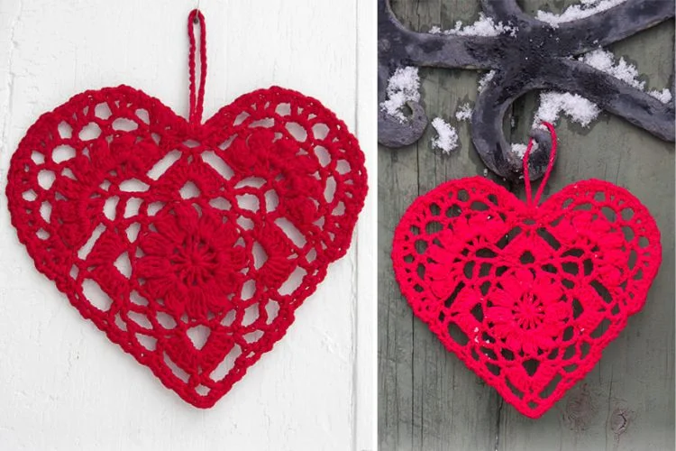 A red crocheted heart hanging on a wooden wall.