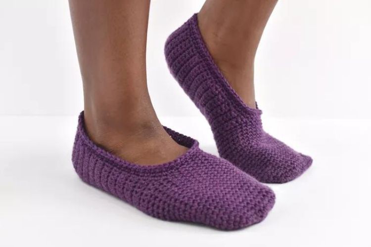 A woman wearing purple knitted slippers.