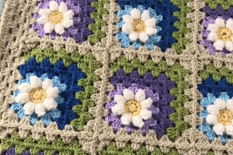 A crocheted afghan with daisies on it.