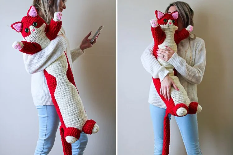 A woman is holding a crocheted cat stuffed animal.