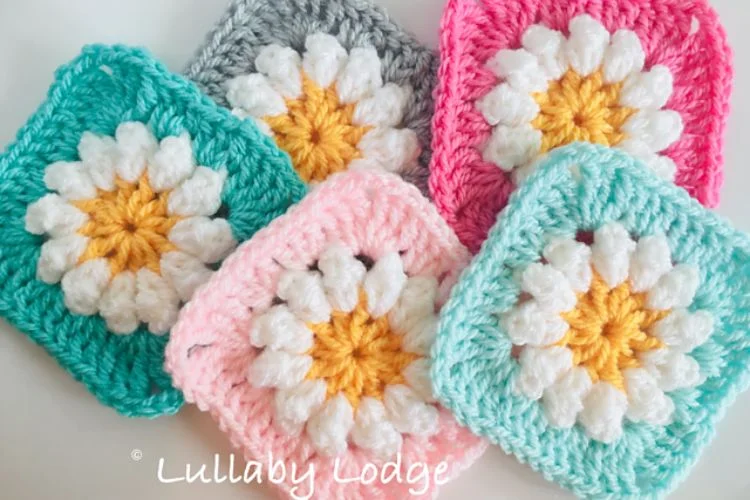 Four crocheted squares with daisies on them.