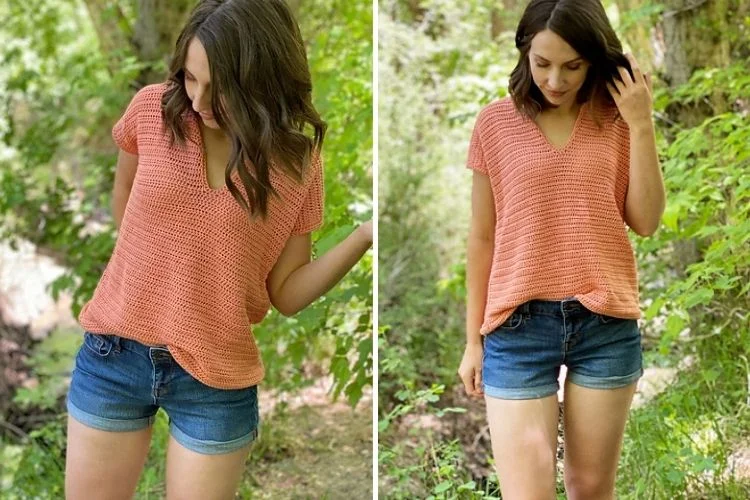 Woman in a coral v-neck top and denim shorts standing in a natural setting.