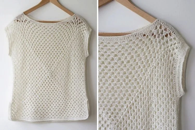 White crocheted top with openwork design displayed on a hanger.