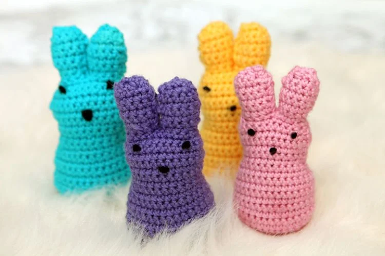 Four crocheted easter bunnies on a white furry surface.