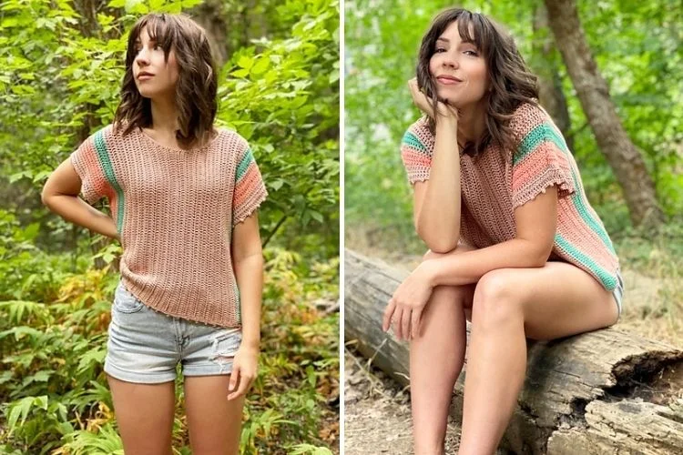 A woman in a knitted top and denim shorts posing in a natural wooded environment.