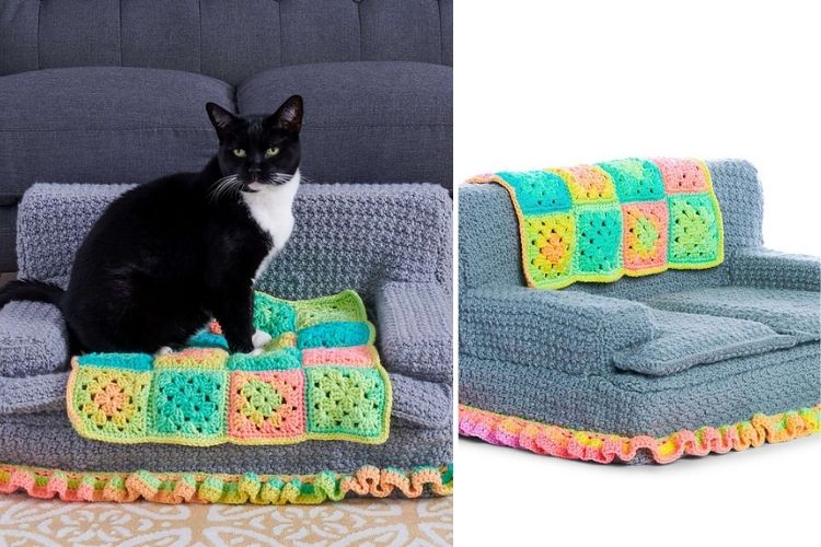 A black and white cat sitting on a miniature sofa with colorful crochet details.