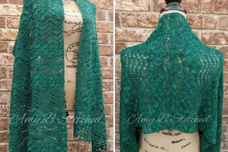 Handcrafted green lace shawl displayed on a dressmaker's mannequin against a brick wall background.