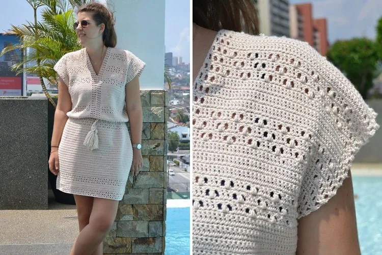 A woman standing by a poolside wearing a white crochet dress showcasing the pattern detail on the sleeve.