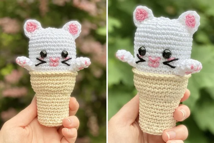 Two crocheted ice cream cone toys resembling cats, one pink and white, the other grey and white, held in a person's hand against a floral background.