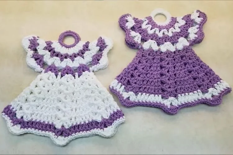 Two crocheted dress-shaped kitchen towels in white and purple colors.