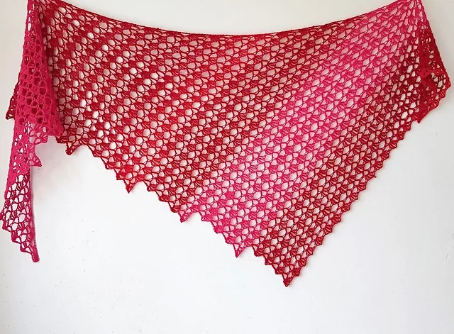 The Hot Chili Shawl, a pink, triangular lace shawl with an openwork crochet pattern, is displayed against a white background.