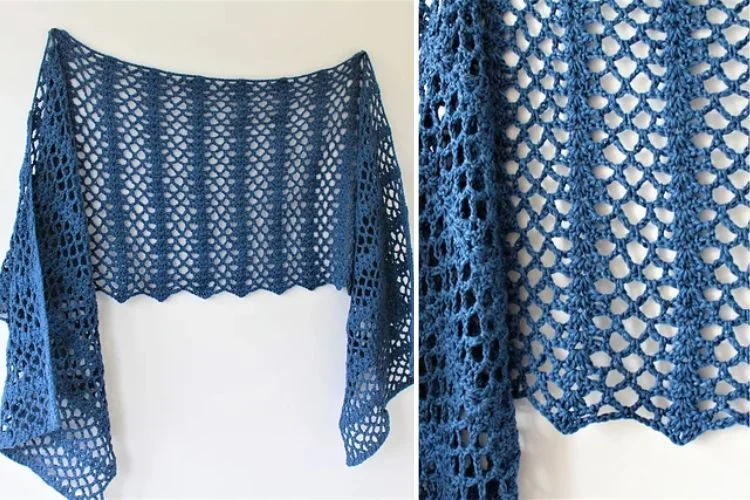 Blue crocheted shawl with an openwork lace pattern displayed against a white background.