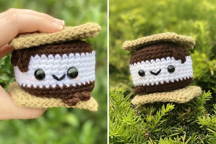 A hand holding a crochet representation of a smiling coffee cup with a green cozy, next to a similar figure placed on a bush.