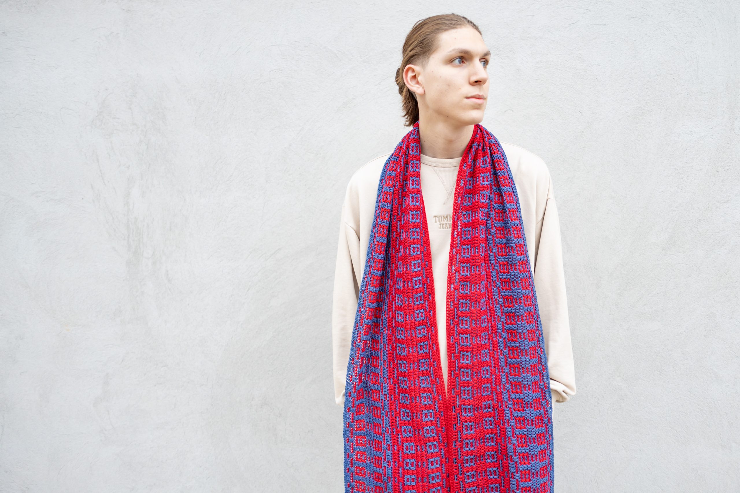 man wearing a long mosaic crochet scarf in blue and red