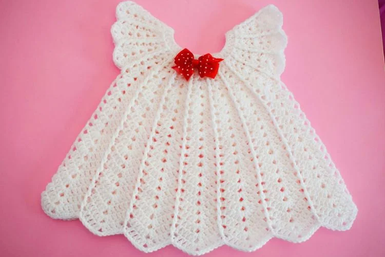 a crochet baby dress with a bow