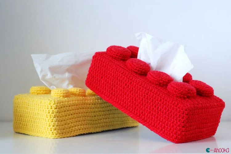 a crochet tissue box cover shaped like a lego brick