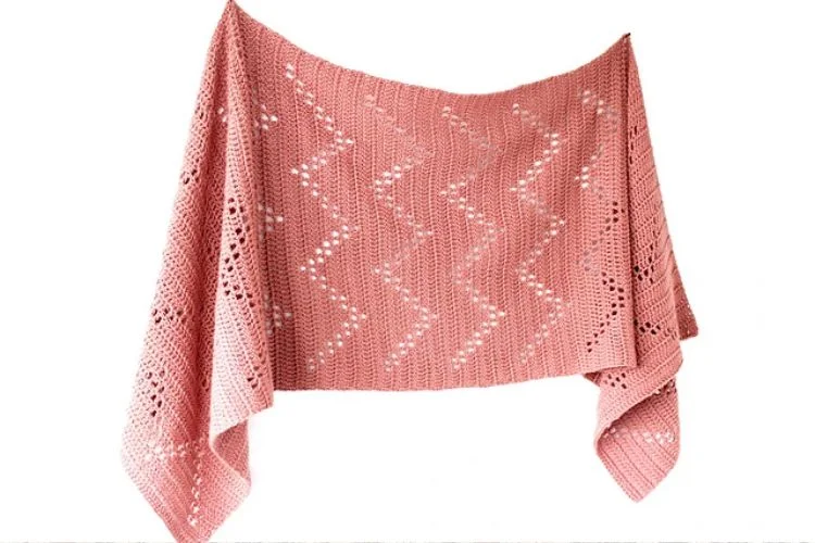 a pink crochet shawl with an openwork design