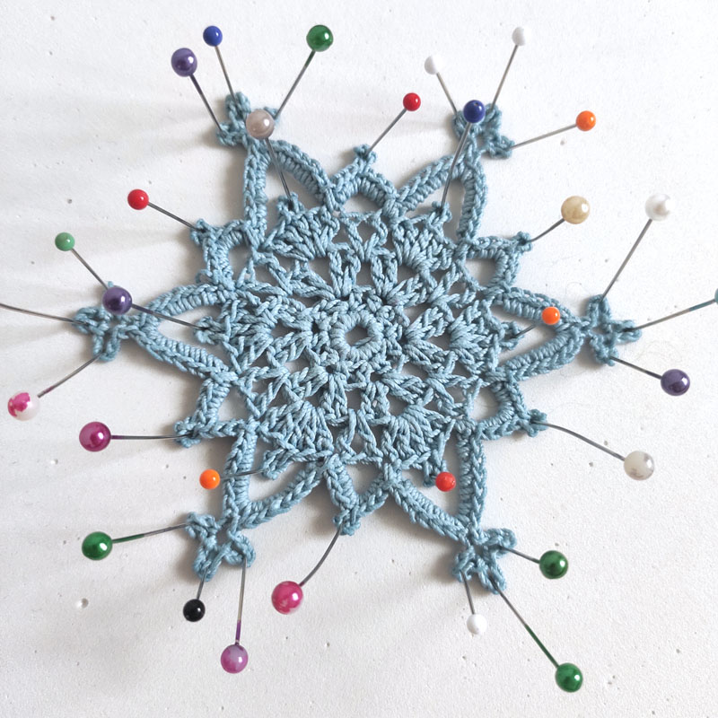 crochet ornament pinned with colorful pins