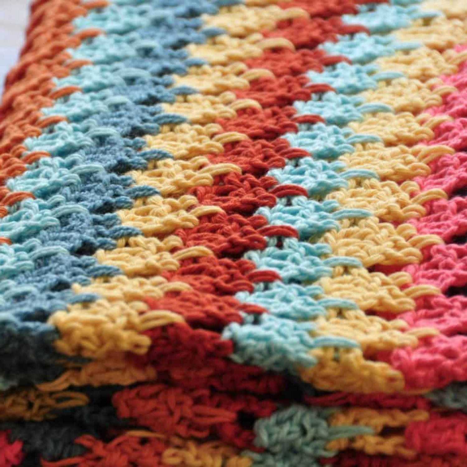 Close-up of a colorful crocheted blanket with a zigzag pattern in red, blue, yellow, and orange hues.