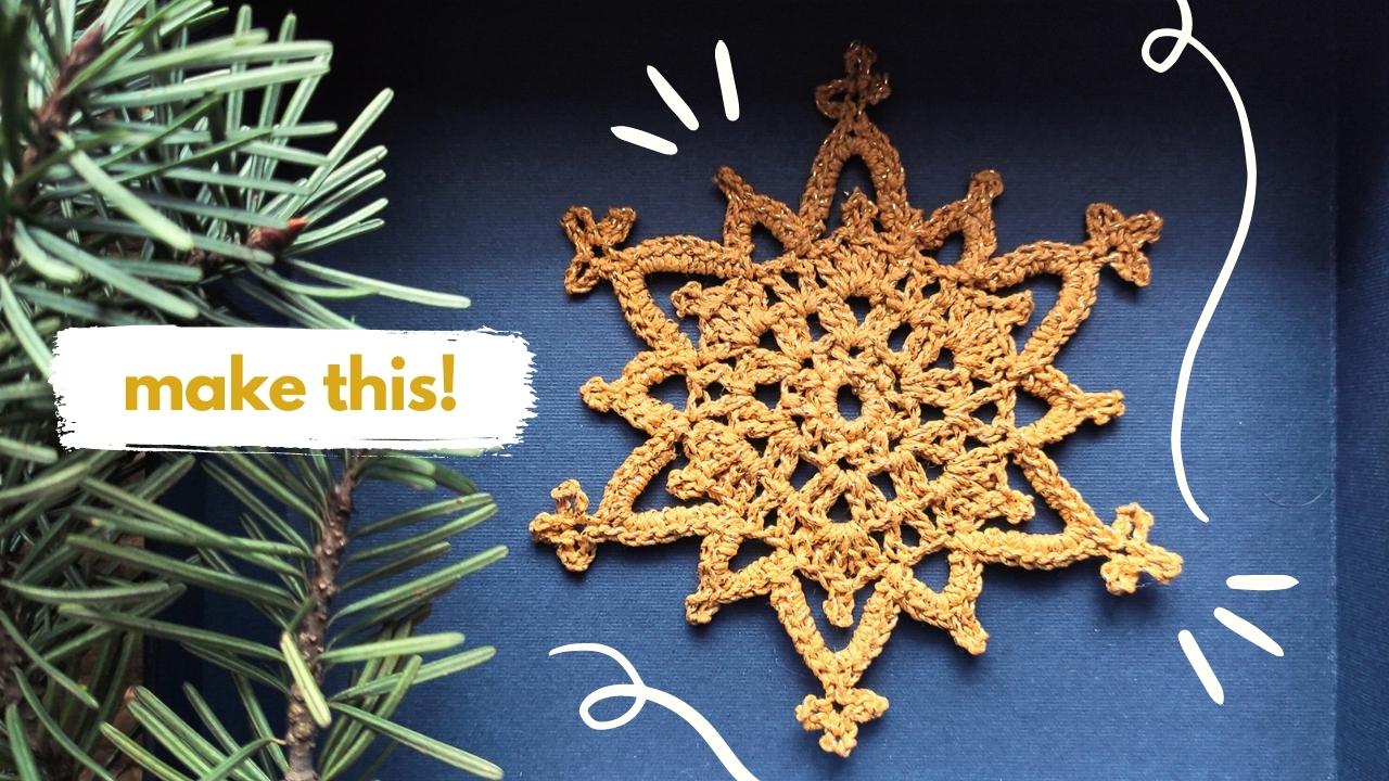 A crocheted crystal snowflake in yellow is displayed next to pine branches on a dark blue background, with the words "make this!" in bold white and yellow text.