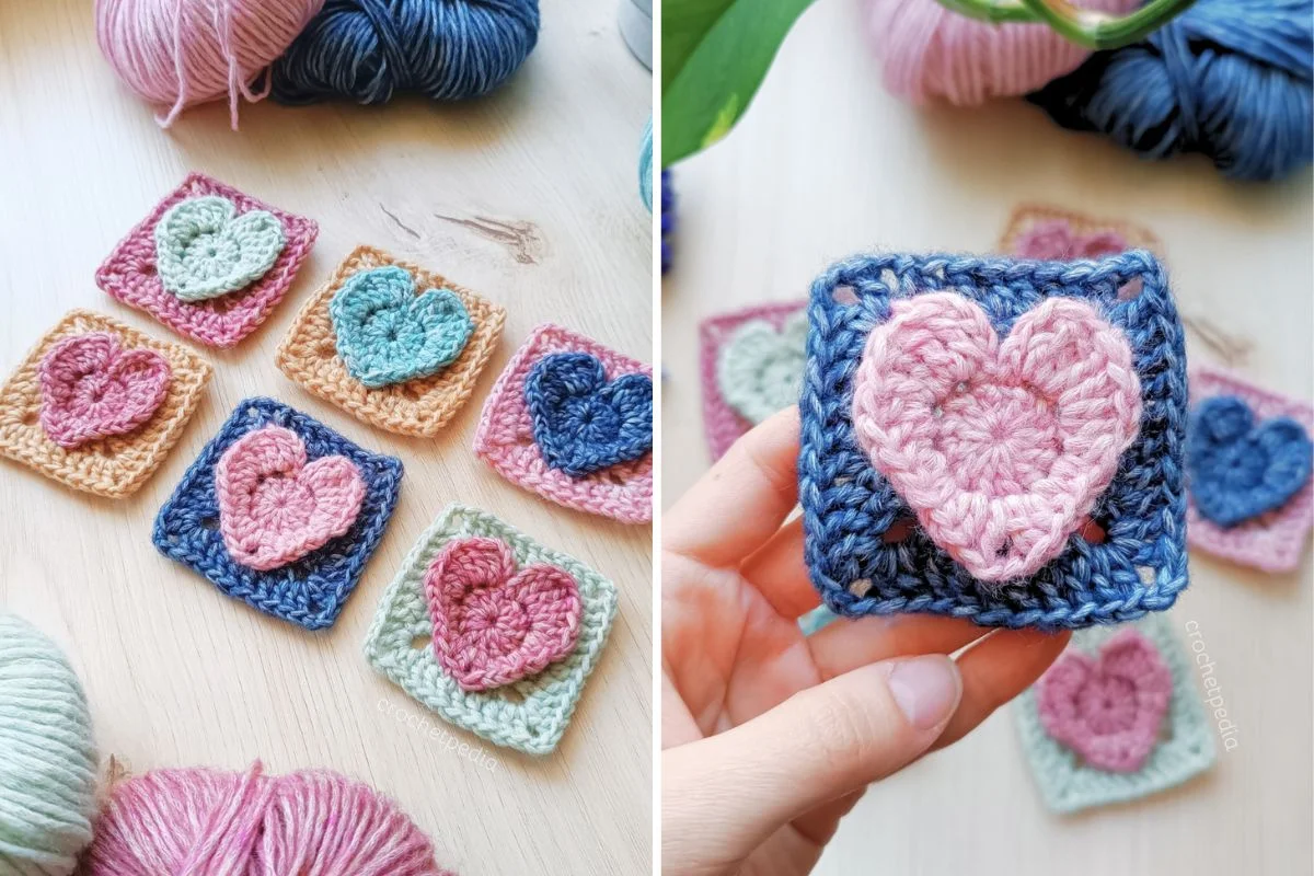 Several colorful crocheted heart squares, reminiscent of classic Granny Squares, are displayed on a wooden surface. One square with a pink 3D Heart on a blue background is held up close. Yarn balls are visible in the background.