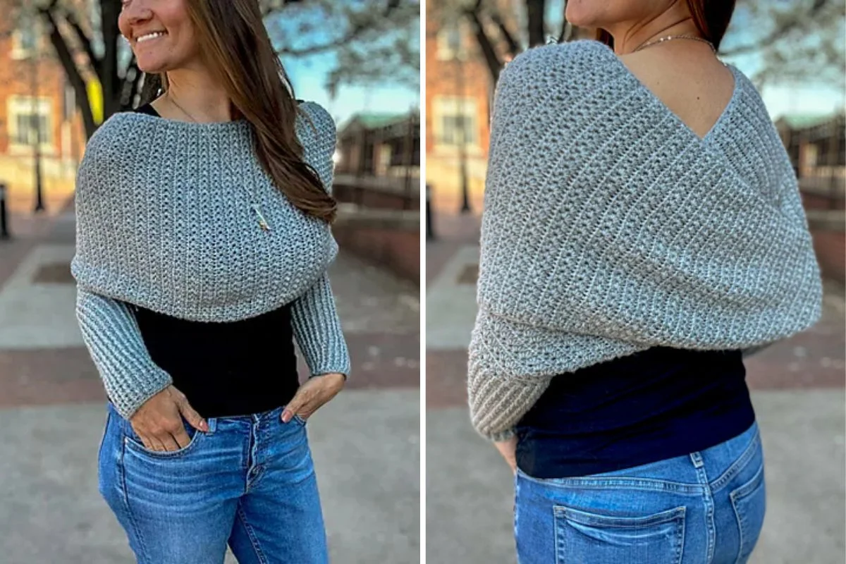 A woman wearing a gray crochet wrap over a black shirt and jeans is standing outdoors. The wrap has a unique design, covering her arms and back.