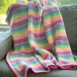 a crochet striped baby blanket in pastel rainbow colors