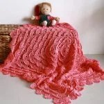 a crochet square baby blanket in a deep pink color
