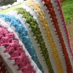 a crochet baby blanket made of rainbow strips