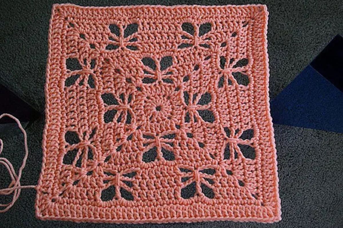 a pink crochet square with lace butterfly motifs