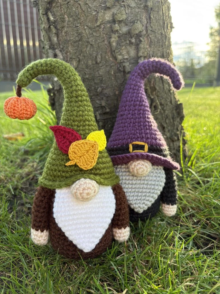 two crochet gnomes standing by the tree