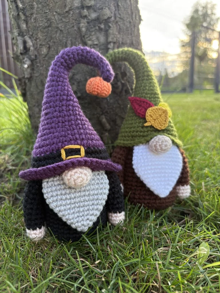two crochet gnomes standing by the tree