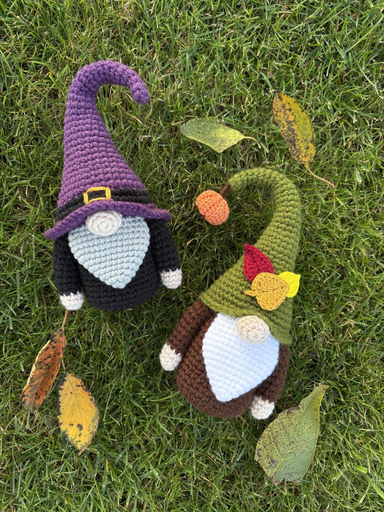 two crochet gnomes laying on the grass