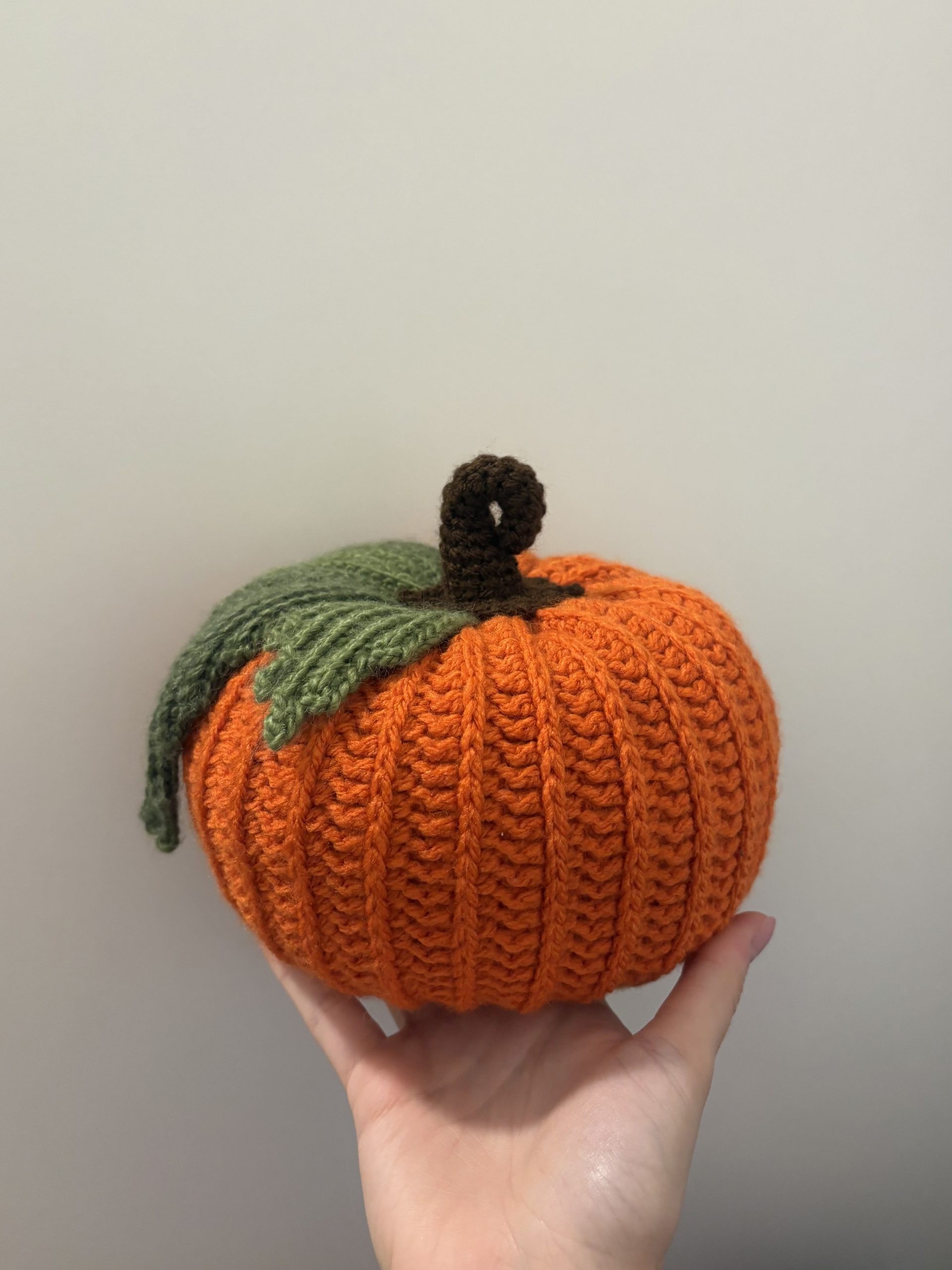 hand holding an orange crochet pumpkin