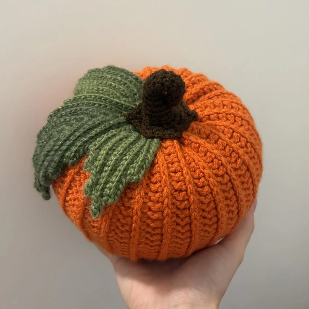 hand holding crochet pumpkin