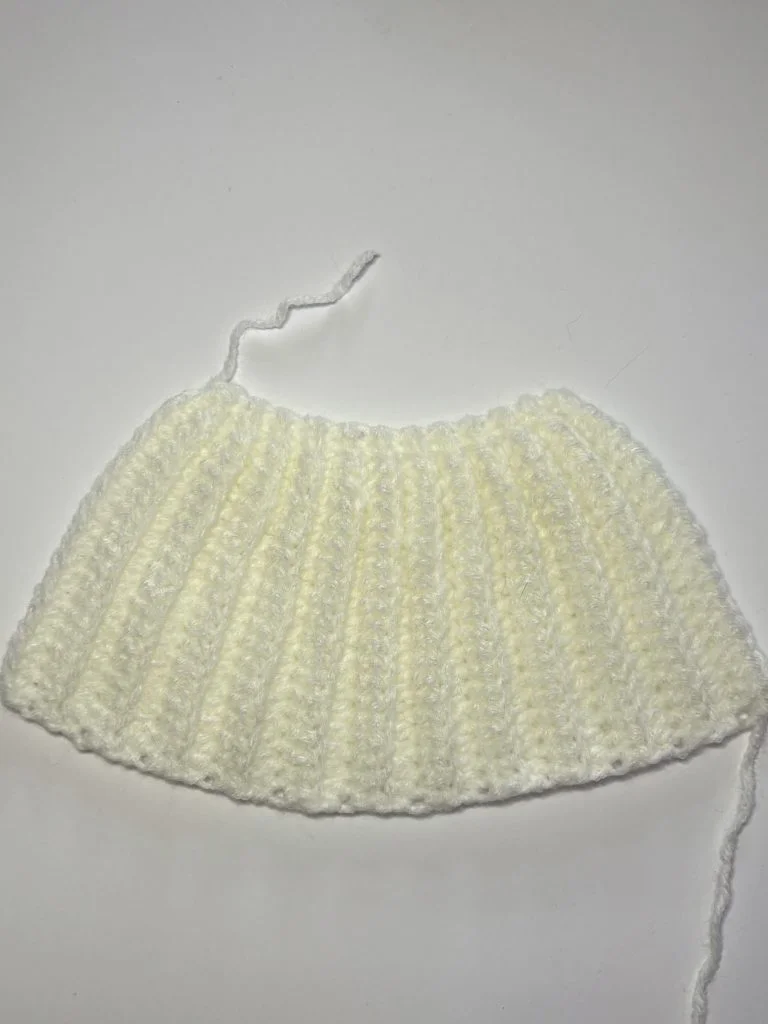 A piece of white ribbed crochet fabric with loose yarn ends, displayed on a plain white background—perfect as a base for your next project using a free crochet pumpkin pattern.