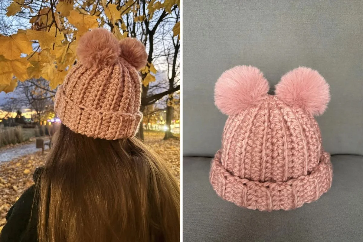 A person wearing a pink crochet hat with two pom-poms stands outdoors; next to it, the same hat is displayed on a gray surface.